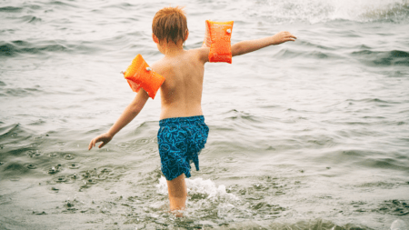 Kind geht mit Schwimmflügeln ins Meer